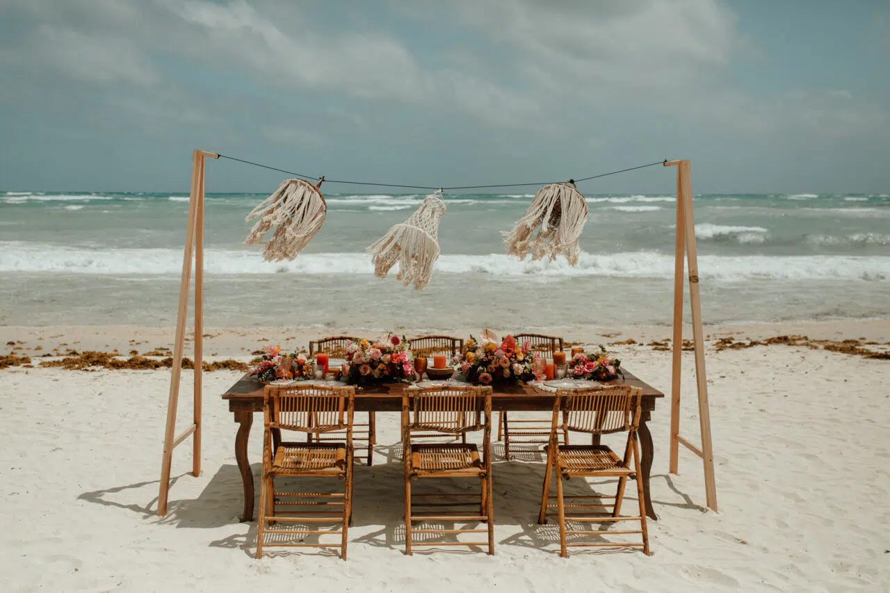 Beachfront table with macramé hangings and the sea behind